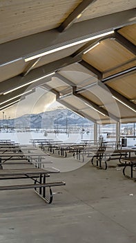 Clear Vertical Covered picnic area and playground at a park blanketed with snow in winter