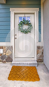 Clear Vertical Facade of a home with a simple leafy wreath hanging on the white front door