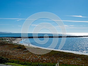 Clear view of beach, rock pathway, grass, rock barrier in sea