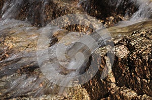 Clear water flows over pink granite rocks