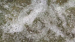 Clear water flows in the rice fields between young rice plants and the water passes through a channel with stones