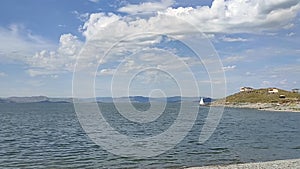 Clear water. Small waves. Mountains in the distance. Clouds. Lake. The yacht is moving.