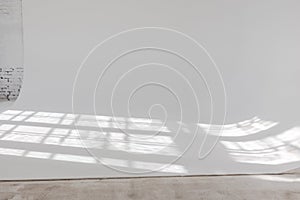 Clear white cyclorama. Light background with sun light and shadows. Plain wall empty photo studio.