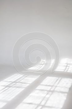 Clear white cyclorama. Light background with sun light and shadows. Plain wall empty photo studio.