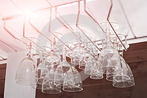 Clear wine glasses hanging in a row over bar rack