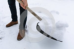 Clearing an area of snow by manual labor, a man removes snow with a shovel