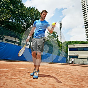 Clearing his mind. a tennis player getting ready to serve.