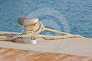 Cleat for mooring boats on wooden platform against a water background