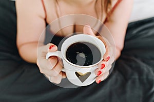 Cleavage or female breasts, young woman drinking a cup of coffee