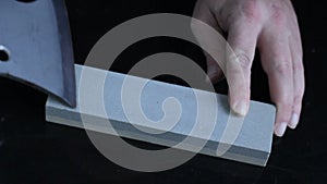 Cleaver narrow knife sharpening on whetstone on background of black boards.