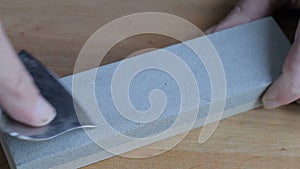 Cleaver narrow knife sharpening on Whetstone on background of wooden boards.