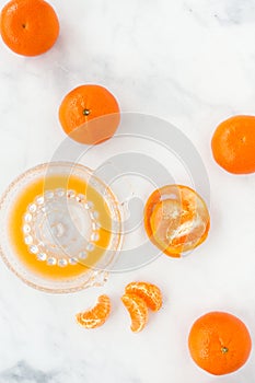 Clementines and Citrus Glass Juicer on White Marble Background