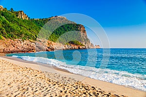 Cleopatra beach on sea coast with green rocks in Alanya peninsula, Antalya district, Turkey. Beautiful sunny landscape for tourism