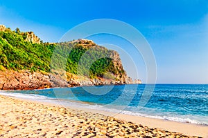 Cleopatra beach on sea coast with green rocks in Alanya peninsula, Antalya district, Turkey. Beautiful sunny landscape for tourism