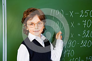 Clever boy holds chalk near blackboard