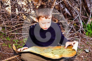 A clever boy searches an ancient map for something buried in a forest