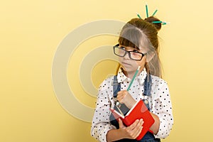 Clever child in eyeglasses holding draw and paint supplies. Kids happy to go back to school.