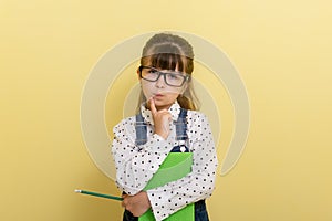 Clever child in eyeglasses holding draw and paint supplies. Kids happy to go back to school.