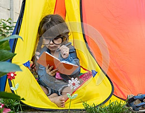 Clever child in eyeglasses holding draw and paint supplies. Kids happy to go back to school. Creative children over yellow backgro