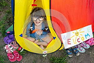 Clever child in eyeglasses holding draw and paint supplies. Kids happy to go back to school. Creative children over yellow backgro