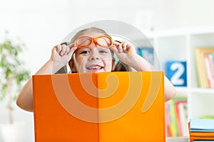 Clever child girl behind of open book indoor