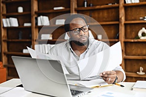 Clever and concentrated African-American guy is doing paperwork photo