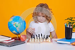 Clever concentrated and thinking child playing chess. Child boy developing chess strategy, playing board game. Kid with