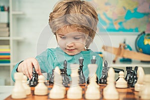 Clever concentrated and thinking child while playing chess. Pupil kid thinking about his next move in a game of chess