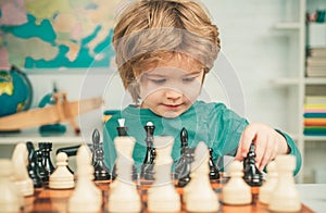 Clever concentrated and thinking child while playing chess. Pupil kid thinking about his next move in a game of chess