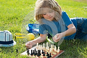 Clever concentrated and thinking kid boy playing chess. Logic game for kids and logical thinking.