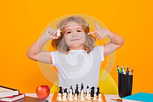 Clever concentrated and thinking kid playing chess. Kids brain development and logic game. Kid with chess on yellow
