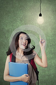 Clever female student pointing at light bulb