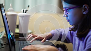 Clever girl in eyeglasses using laptop for studying at home