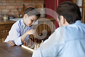Clever junior school age boy playing chess with dad