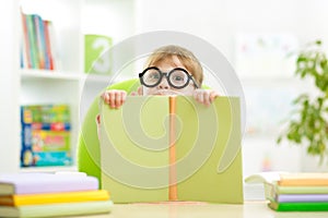 Clever kid little girl behind of open book indoor