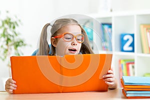 Clever kid little girl behind of open book indoor