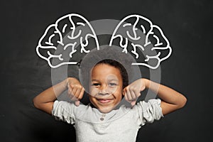 Clever kid student on blackboard background, brainstorming and brain power concept