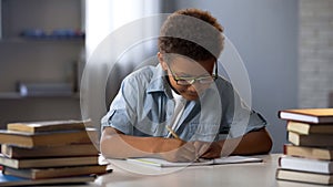 Clever male pupil doing math homework, solving equation in notebook, knowledge