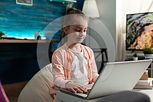 Clever schoolchild working at literature homework browsing educational information