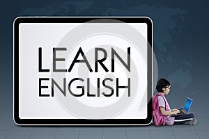 Clever schoolgirl sits near word of Learn English