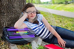 Clever student teen girl with school bag under park tree
