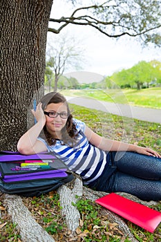 Clever student teen girl with school bag under park tree