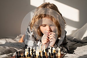 Clever thinking child. Little kid play chess. Thinking child. Chess game for kids. Intelligent, smart and clever school