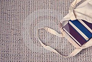 Clever weighty books in textured blue and lilac fabric covers lie in an open linen bag.