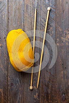 Clew of yellow wool yarn knitting needles on aged plank wood background. Crafts hobby clothes making fashion concept