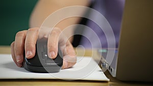 Click black computer mouse on a work desk. Working with a PC or laptop at workplace, close-up