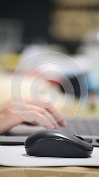 Click black computer mouse on a work desk. Working with a PC or laptop at workplace, close-up