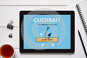 Clickbait concept on tablet screen with office objects