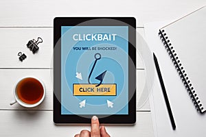 Clickbait concept on tablet screen with office objects