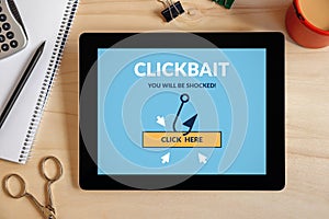 Clickbait concept on tablet screen with office objects